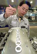 An employee of South Korea's Daewoo Motor looks at an engine