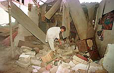 A man sifts through the debris of his collapsed house 