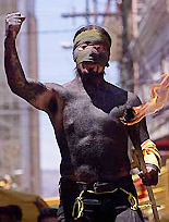 A Honduran wearing make-up and carrying a torch takes part in a May Day demonstration