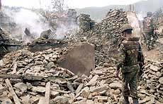 Soldiers walk through the debris of gutted residential houses