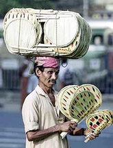 Moharram Sardar, a fan vendor, crosses a road while keeping himself cool
