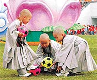 Young Buddhist monks play with small soccer balls 