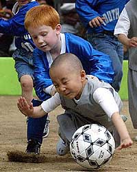 Young Buddhist monks and children from the U.S play a soccer game at the Chogye temple in Seoul on Tuesday.