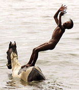 A young horse-keeper playfully jumps off his employer�s horse