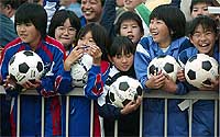A group of Japanese girls wait to have their soccer balls autographed