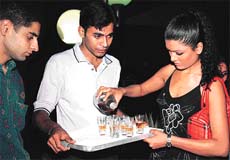 Koena Mitra pours Chivas Regal in shot glasses before going on a round of tables