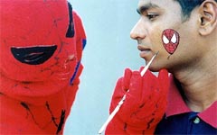 A person dressed as "Spider-Man" paints a tattoo