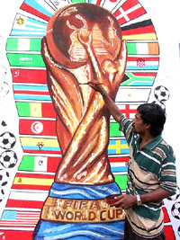 An artist gives the finishing touches on a mural of the World Cup