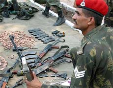 An Indian soldier displays arms and ammunition recovered from militants