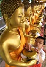 A boy donates money at a Buddhist temple