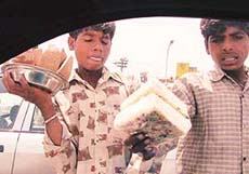 Young boys sell coconut slices at a traffic light point, in Ludhiana.