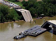 Two barges sit under a collapsed section of an interstate highway bridge