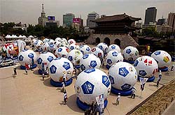 People walk around 32 giant soccer balls