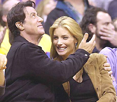 Actor Sylvestor Stallone hugs his wife, model Jennifer Flavin, as they watch the NBA game