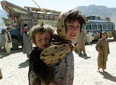 An Afghan girl carries her brother at the Puli Charkhi refugee camp, 20 km east of Kabul, in this May 24 file photo.