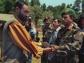 A militant lays down his arms before an Army officer