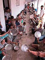 Migrants wait for their turn to get their meal