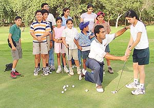 Ajay Gujral teaches golf techniques to youngsters at the Chandigarh Golf Club on Tuesday.�