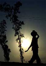 A migrant woman carries drinking water