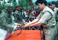 One of the 12 militants handing his gun to an officer