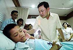 Thai Prime Minister Thaksin Shinawatra consoles a school boy