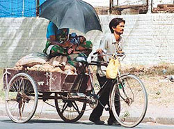 HEAT SHIELD MADE OF TENDER LOVE: Shielding his family from the scorching sun, a labourer braves all the heat himself.