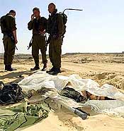 Israeli soldiers stand beside the body