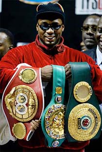 Lennox Lewis holds his championship title belts 