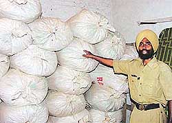 A policeman points at the sacks of poppy husk