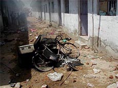 Burnt vehicles and household belongings lie on the road