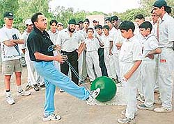 Dr Ravinder Chadha exercises with the exercise tube as trainee cricketers watch at Govt Senior Secondary School, Sector 19, coaching camp in Chandigarh on Wednesday.