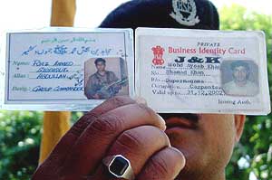 A jawan shows two identity cards of a Pakistani national