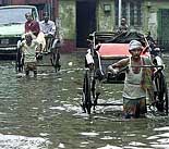 A rickshaw-puller crosses a flooded street in Kolkata