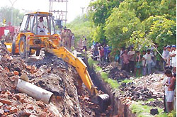 A bulldozer removing the debris of the wall of a drain that collapsed burying three persons at Vinod Nagar in IP Extension on Wednesday in the Capital. 