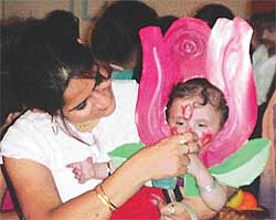 A mother feeds her child dressed up as a rose in a fancy dress show 