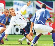 England's David Bechkam (c) falls in front of Brazil's Gilberto Silva (L) and Edmilson (R) during their quarter-final match at the World Cup in shizuoka on Friday. 