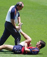 Spain's national soccer team star player Raul Gonzalez, with his right thigh in a bandage, gets help stretching from trainer Pedro Chueca during a training session on Friday