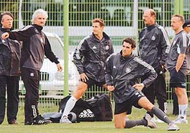 German national soccer team coach Rudi Voeller (L) talks to the team as Miroslav Klose (C) and Christoph Metzelder (R), flanked by two physiotherapists stretch during a training session in Sogwipo