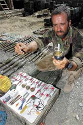 Staff Sergeant Colin Hill of the British Royal Engineers Bomb Disposal unit shows a booby trap device