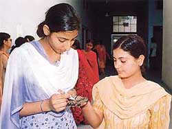 A girl applies mehndi in a competition organised during the NSS camp at Guru Nanak National College