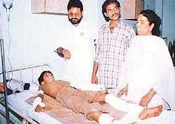Chintu, who was bitten by a pig, lies on a bed in hospital His parents and the area councillor stand beside him.