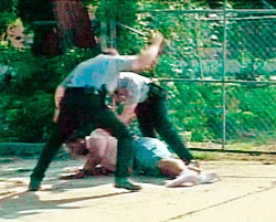 Two white Oklahoma City police officers, one of them wielding a police baton, try to subdue a black suspect lying on the ground in this video image from footage released on Wednesday. 