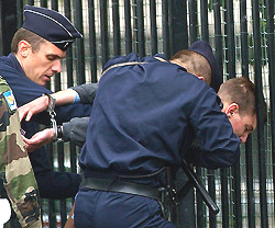 French police hold an unidentified man caught carrying a rifle in crowd of onlookers at the start of the Bastille Day parade on the Champs Elysees in Paris on Sunday.