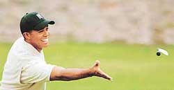 US golfer Tiger Woods smiles as he throws his club to his caddie during a practice round for the British Open Golf Championship