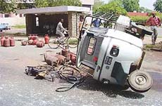 A three-wheeler carrying the LPG cylinders overturns