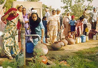 Women and children await their turn for water on the outskirts of Bathinda