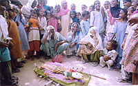 Women perform the ritual of burning a 'guddi' to appease the rain god at Poohla village of Bathinda on Friday.