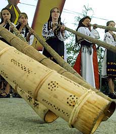 Romanian girls, dressed in traditional costumes, play "tulnic"