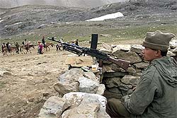 A BSF man keeps watch over pilgrims as they ply the route to the holy cave of Amarnath at Sheshnag in Jammu and Kashmir on Saturday.