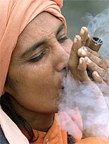 A holy woman smokes a clay pipe (chilam) along the route of a pilgrimage at Panjtarni in Jammu and Kashmir on Saturday.
